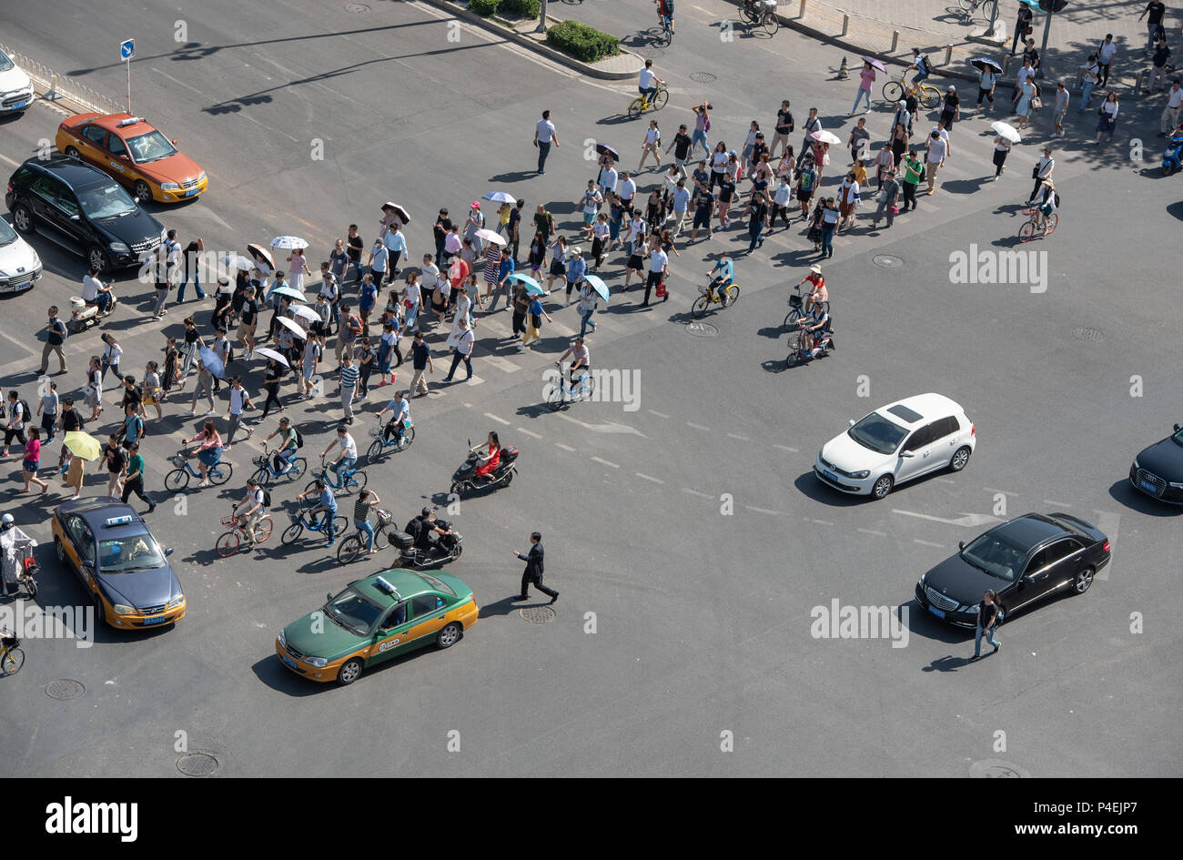 Beijing, Asia – June 4 2018: Group of people crossing a high traffic avenue with cars and bicycles in the city of Beijing in China Stock Photo