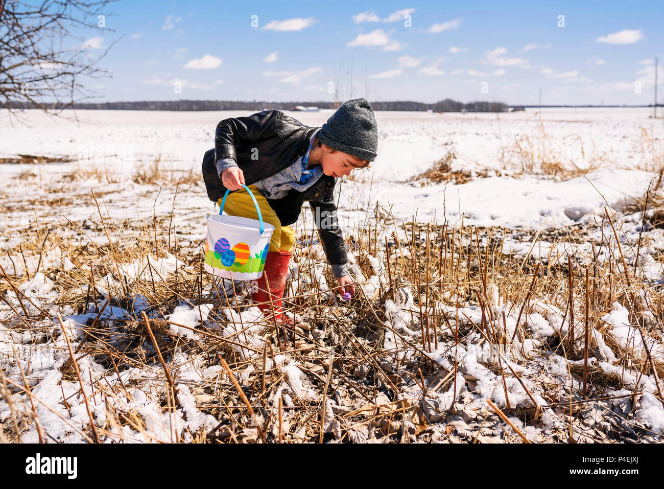 Boy on an Easter egg hunt in the snow Stock Photo
