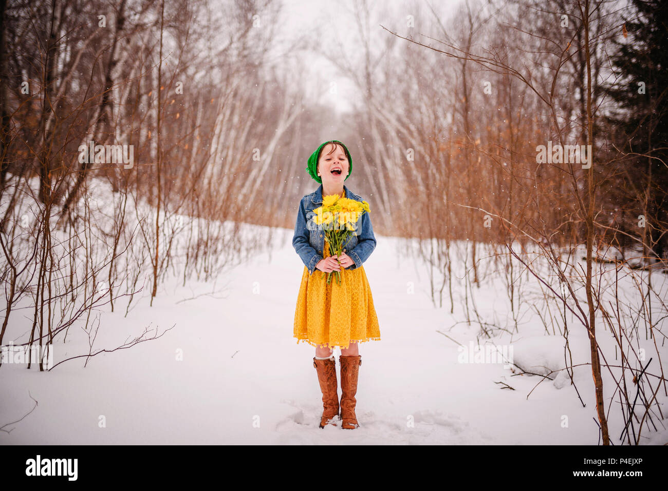 Girl standing in the snow holding a bunch of flowers Stock Photo
