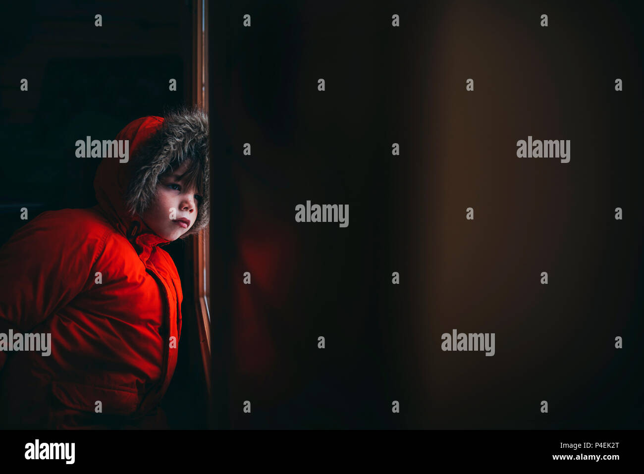 Boy wearing a winter jacket standing by the front door Stock Photo