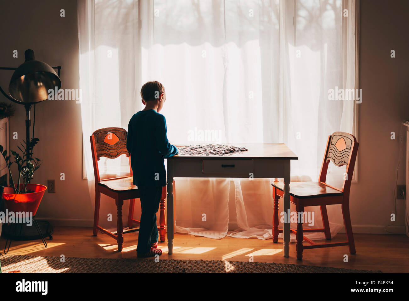 Boy standing by a table doing a jigsaw puzzle Stock Photo