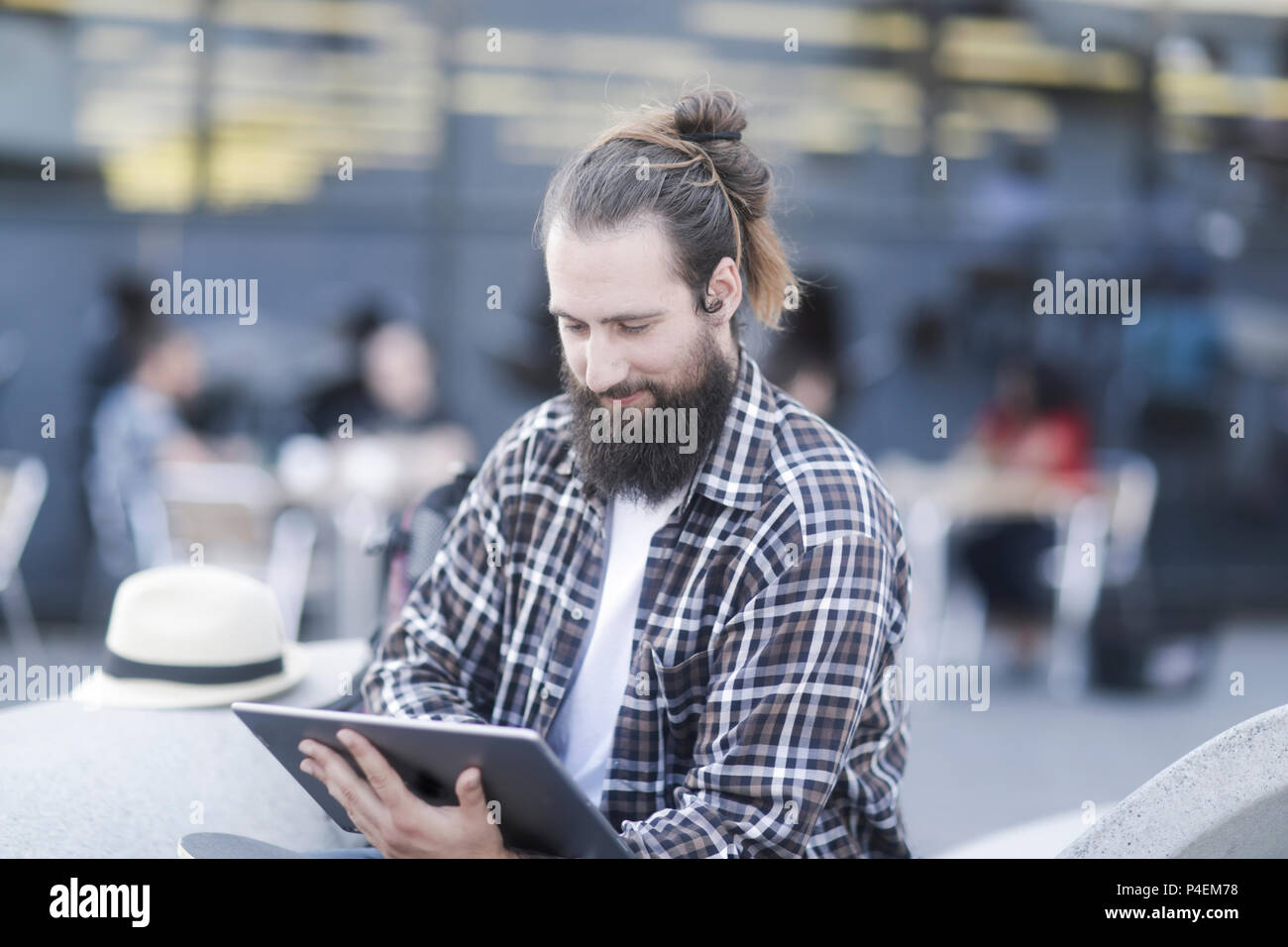 Smiling Man sitting outdoors using a digital tablet Stock Photo