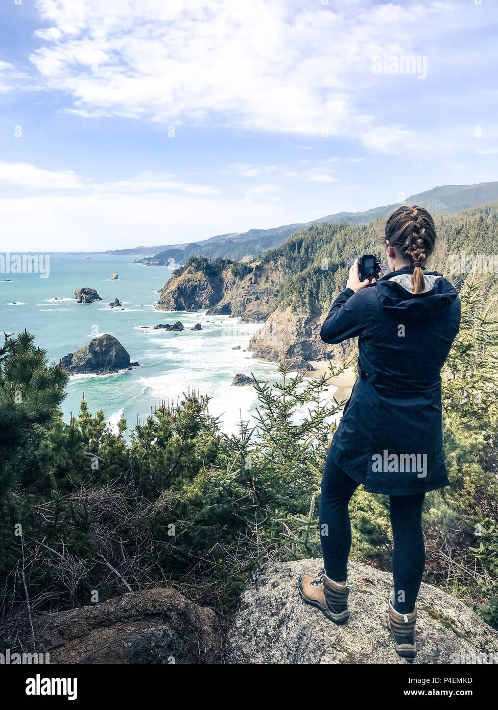 Woman standing on cliff taking a photo of the ocean, Brookings, Oregon, America, USA Stock Photo