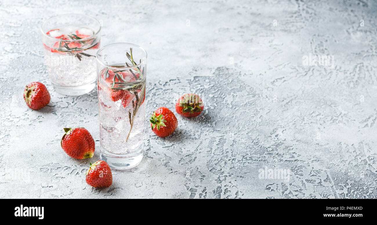 Alcoholic or non-alcoholic cocktail with strawberries and rosemary and ice in glass glasses. Free space for text. Banner Concept Stock Photo