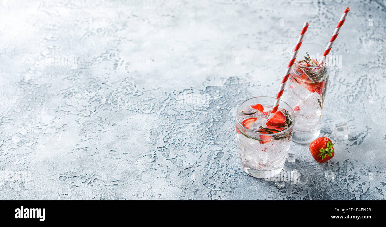 Alcoholic or non-alcoholic cocktail with strawberries and rosemary and ice in glass glasses. Free space for text. Banner Concept Stock Photo