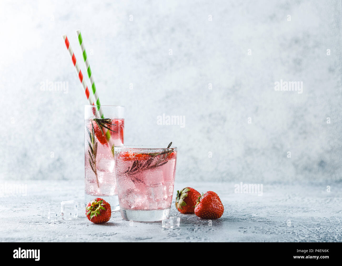 Alcoholic or non-alcoholic cocktail with strawberries and rosemary and ice in glass glasses. Free space for text. Stock Photo