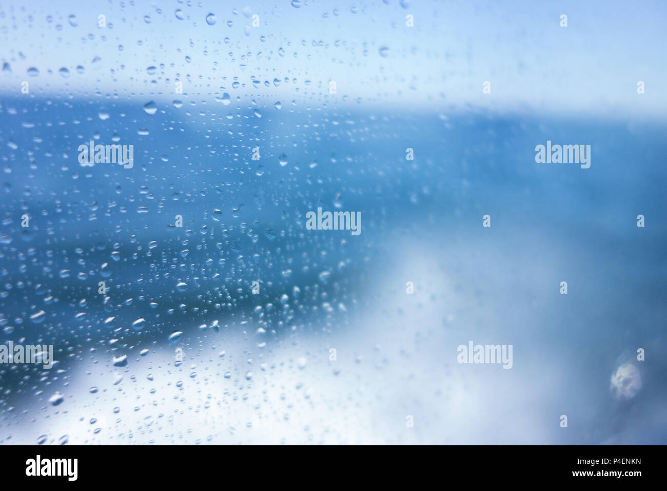 Water droplets on the window of a ship, with a blue sea background Stock Photo