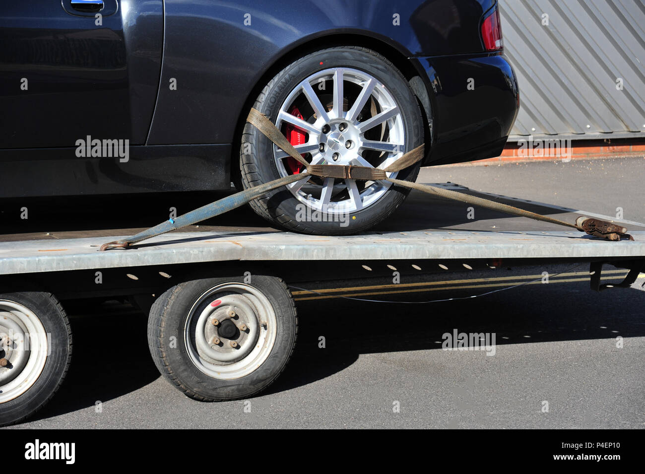 Dark car secured onto the back of a car trailer Stock Photo Alamy