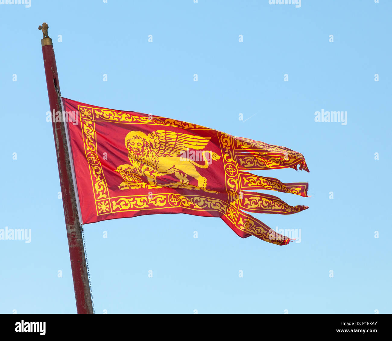 Venetian flag with Lion of St Mark  flying against a sunny blue sky, Venice, Veneto, italy Stock Photo
