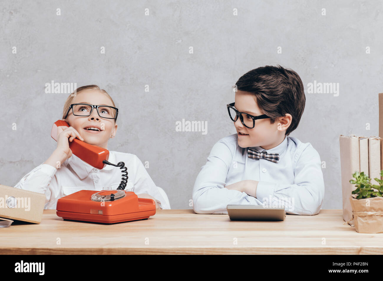 portrait of little girl talking on telephone while boy sitting near by at workplace Stock Photo