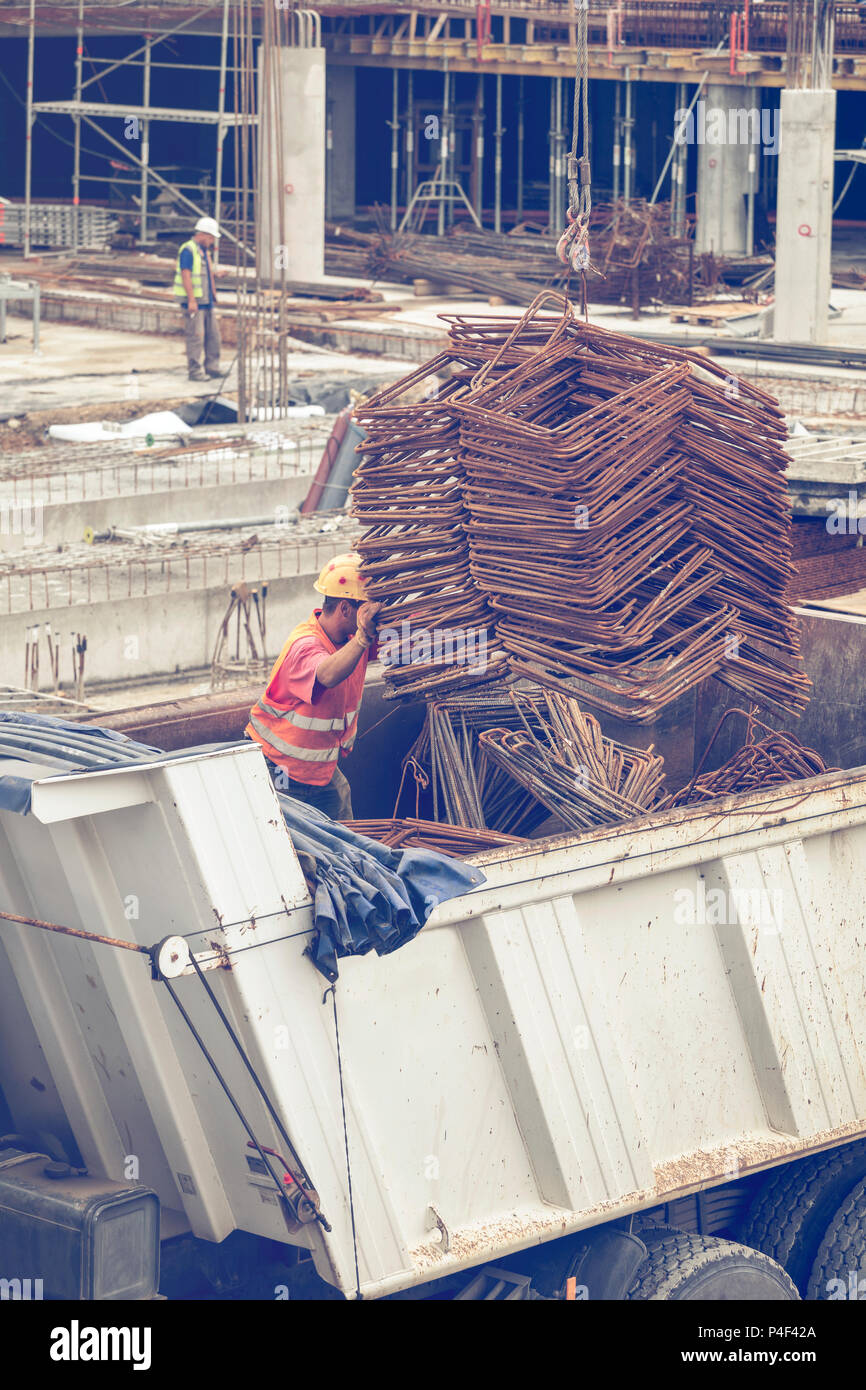 Crane lifter handling bundles of angled rebar loading on delivery truck