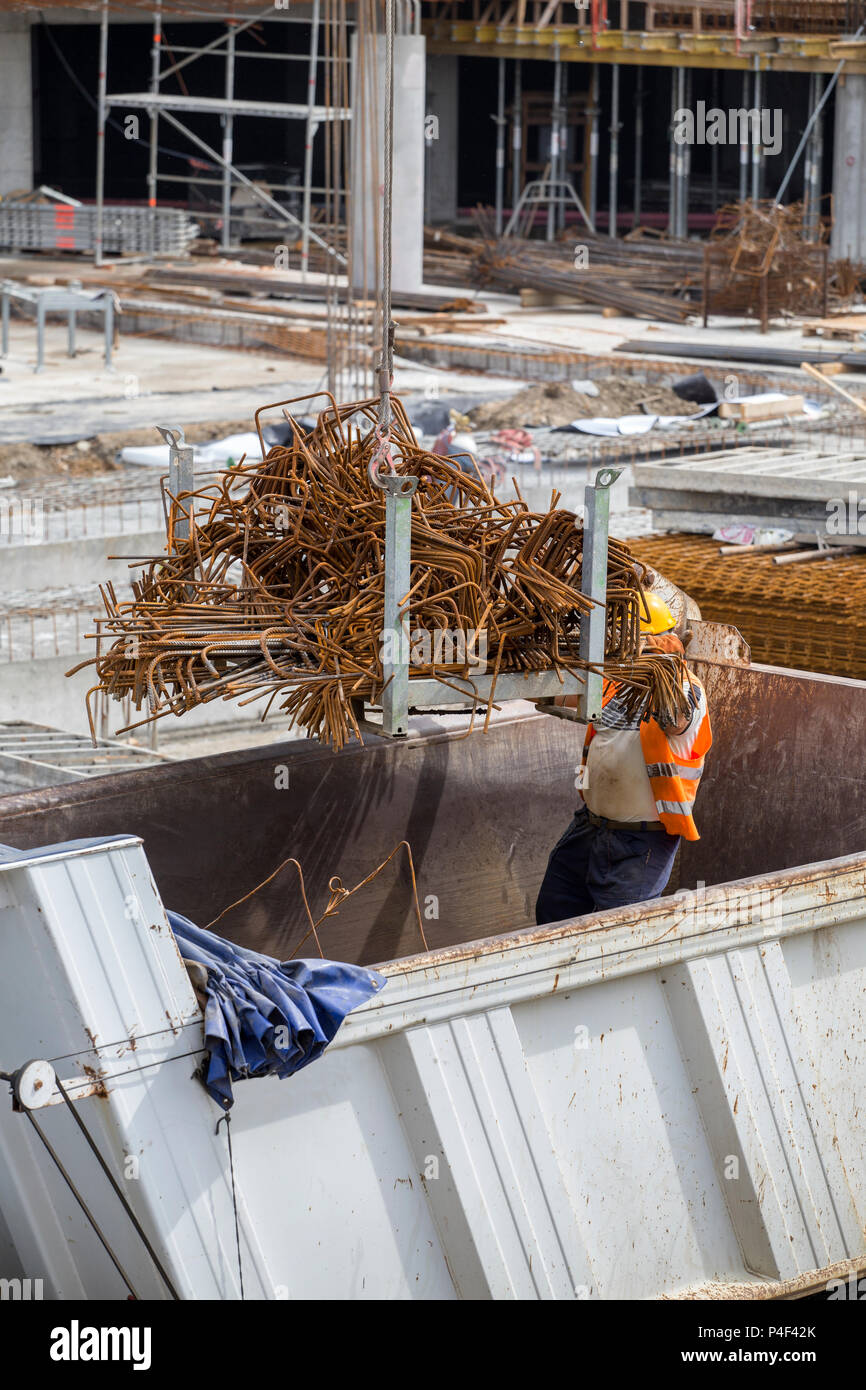 Crane lifting up a load of steel rebar from big truck at construction