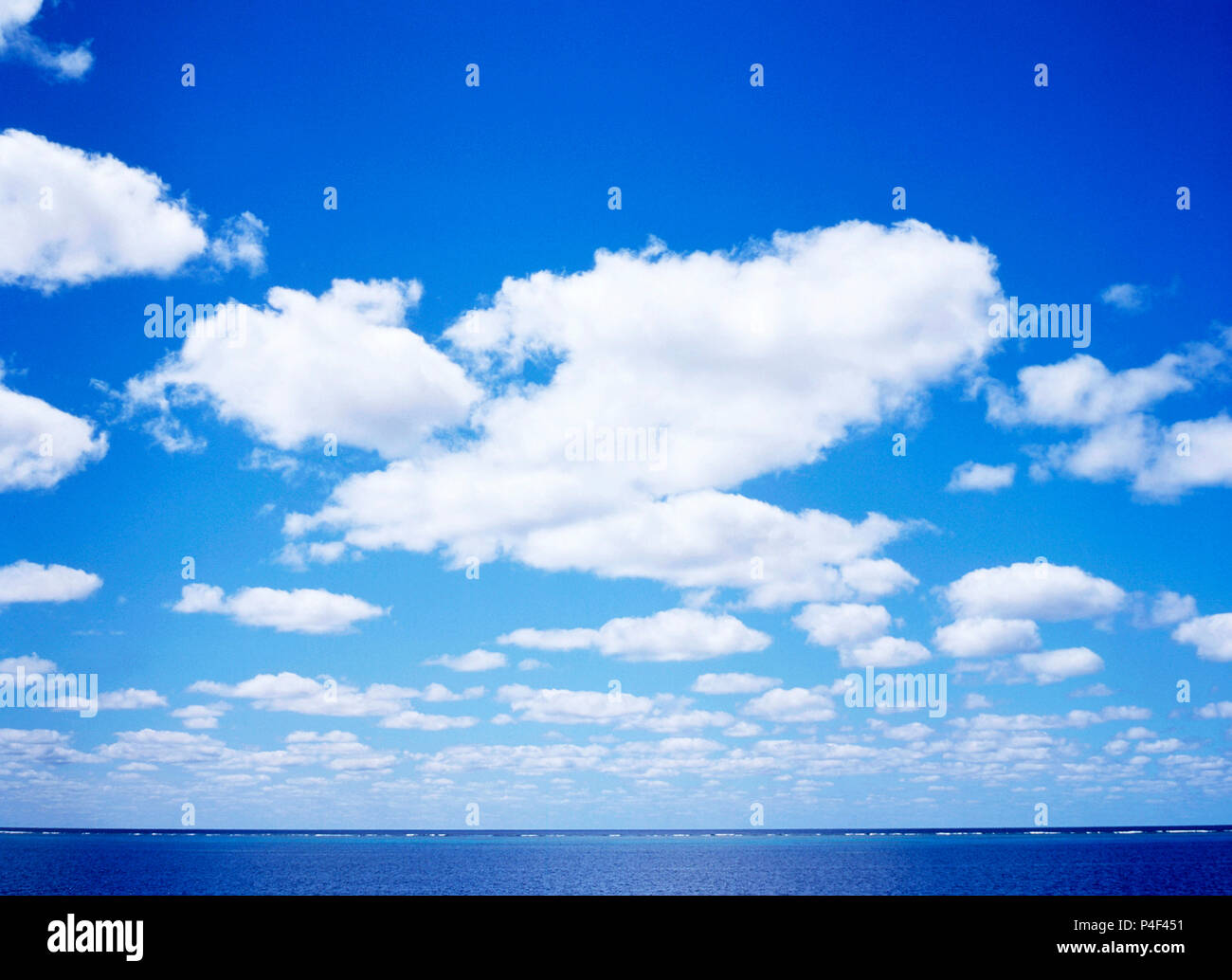 Blue sky with fluffy white clouds over Pacific Ocean horizon of Great Barrier Reef, Queensland, Australia. Stock Photo