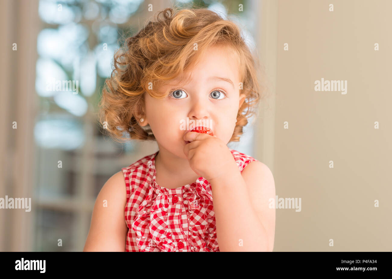 Beautiful Blonde Child With Blue Eyes Eating Strawberry At Home