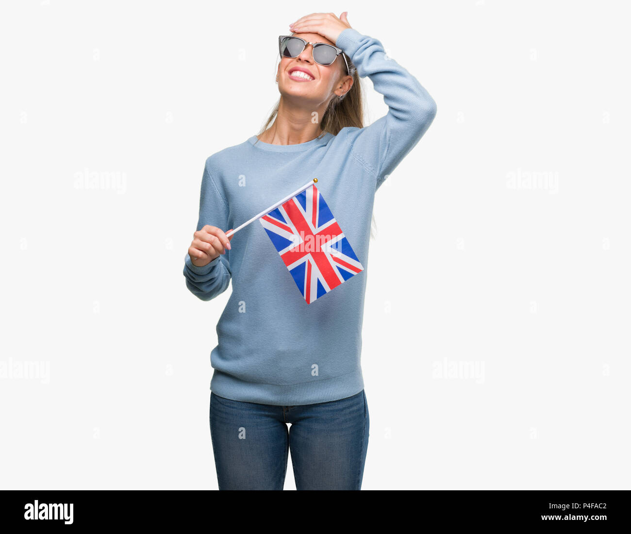 Beautiful young woman holding UK flag stressed with hand on head, shocked with shame and surprise face, angry and frustrated. Fear and upset for mista Stock Photo