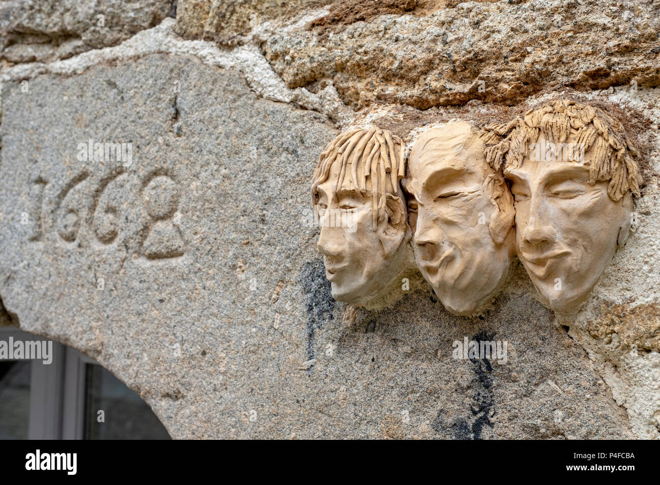 Clay faces sculpted on a wall above a doorway dated 1668 in Huelgoat, Brittany, France. Stock Photo