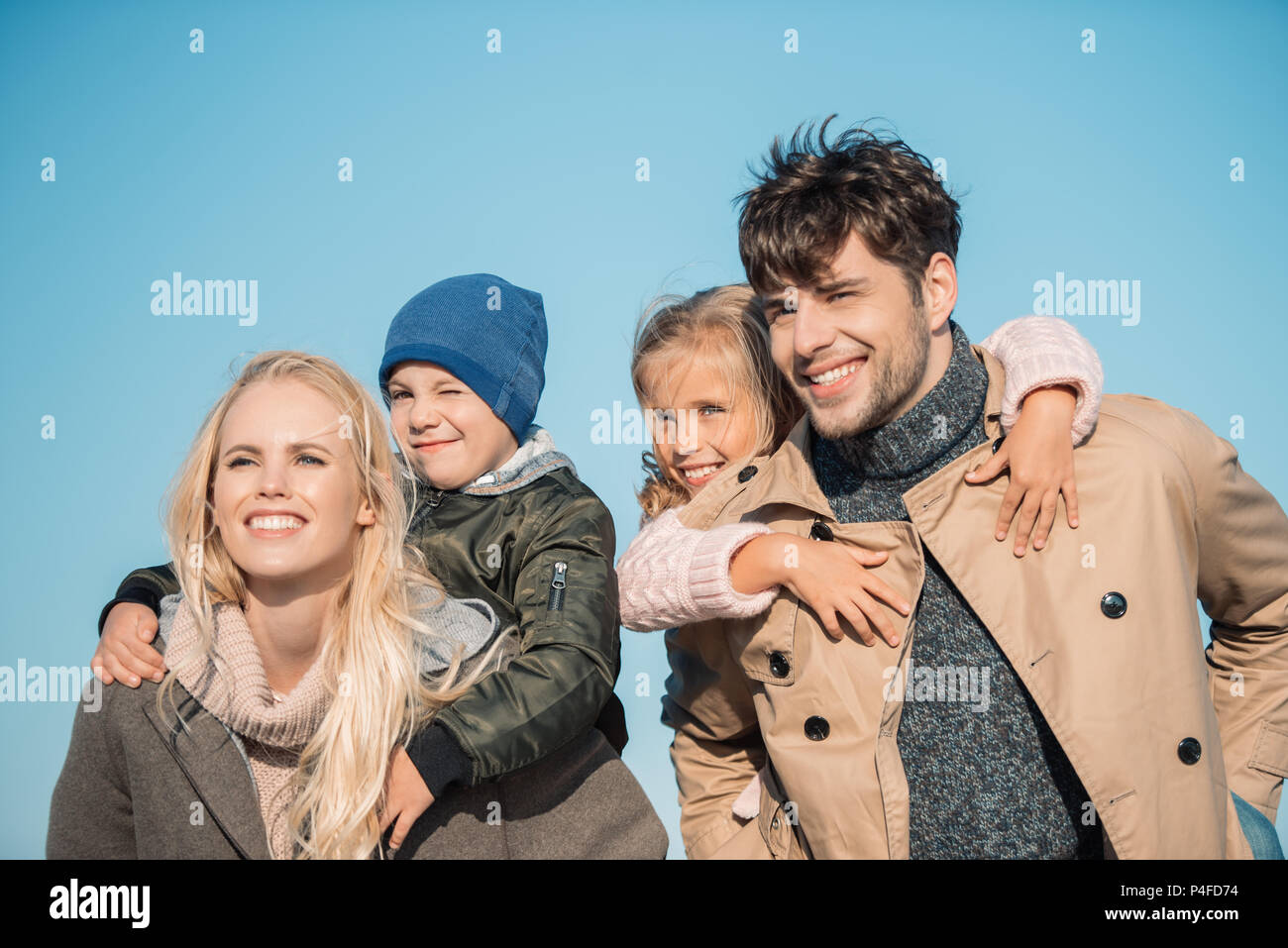 portrait of smiling parents piggybacking their children Stock Photo