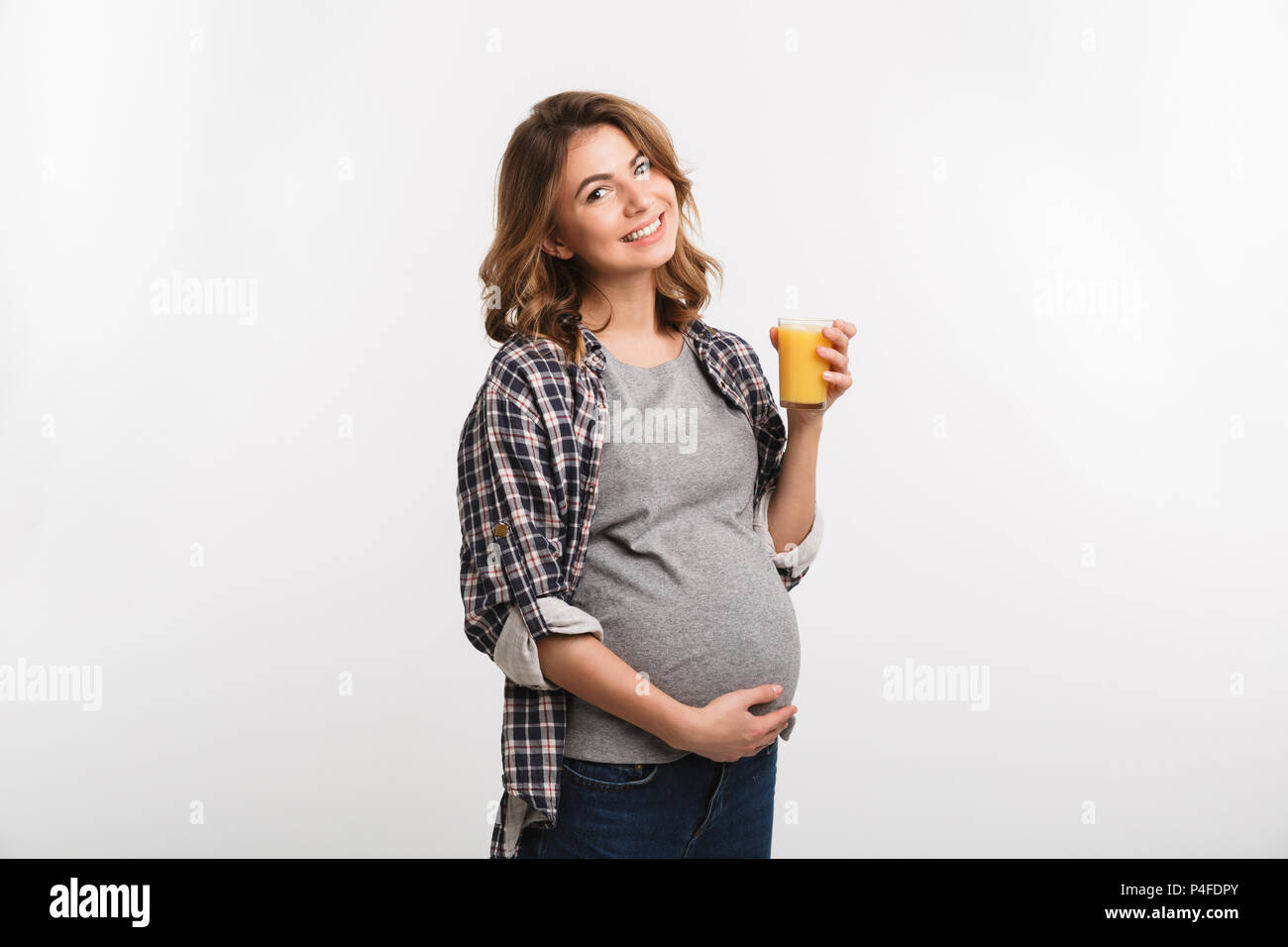 beautiful young pregnant woman holding glass with juice and smiling at ...