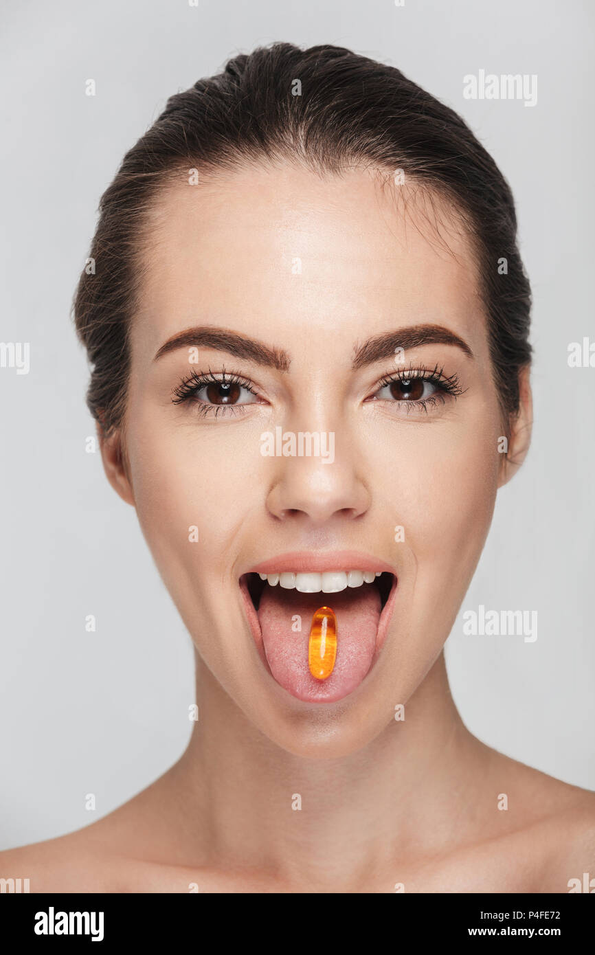 attractive young woman with fish oil capsule in mouth isolated on white Stock Photo