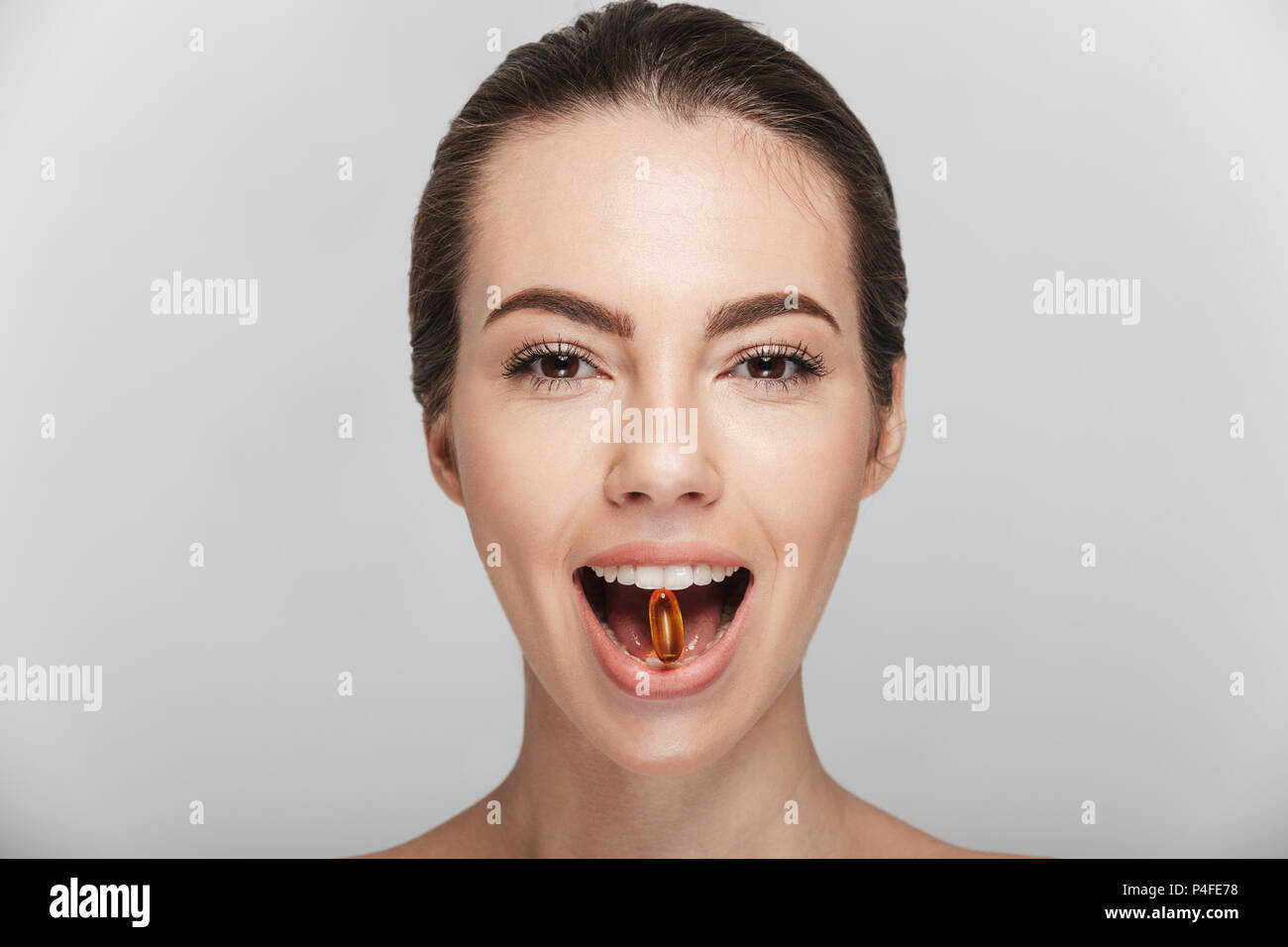young woman with fish oil capsule in mouth isolated on white Stock Photo