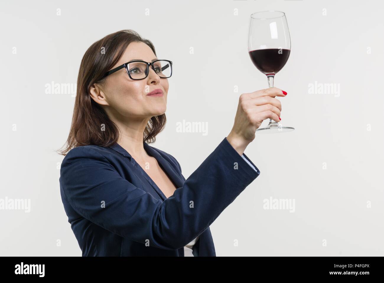 Business woman is holding and looking at a glass of red wine. White ...