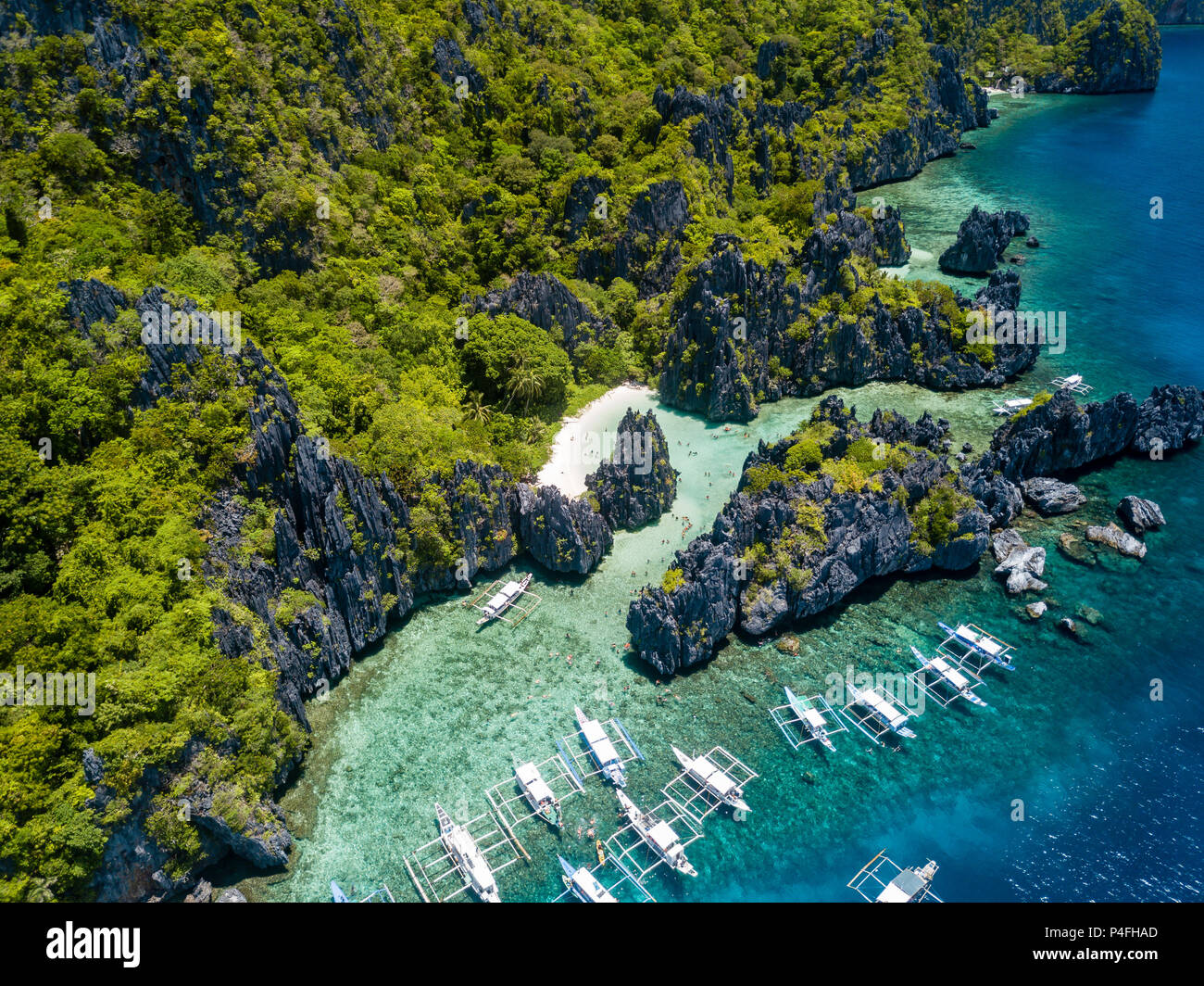 Aerial drone view of boats over a tropical coral reef and remote sandy beach (Hidden Beach, El Nido) Stock Photo