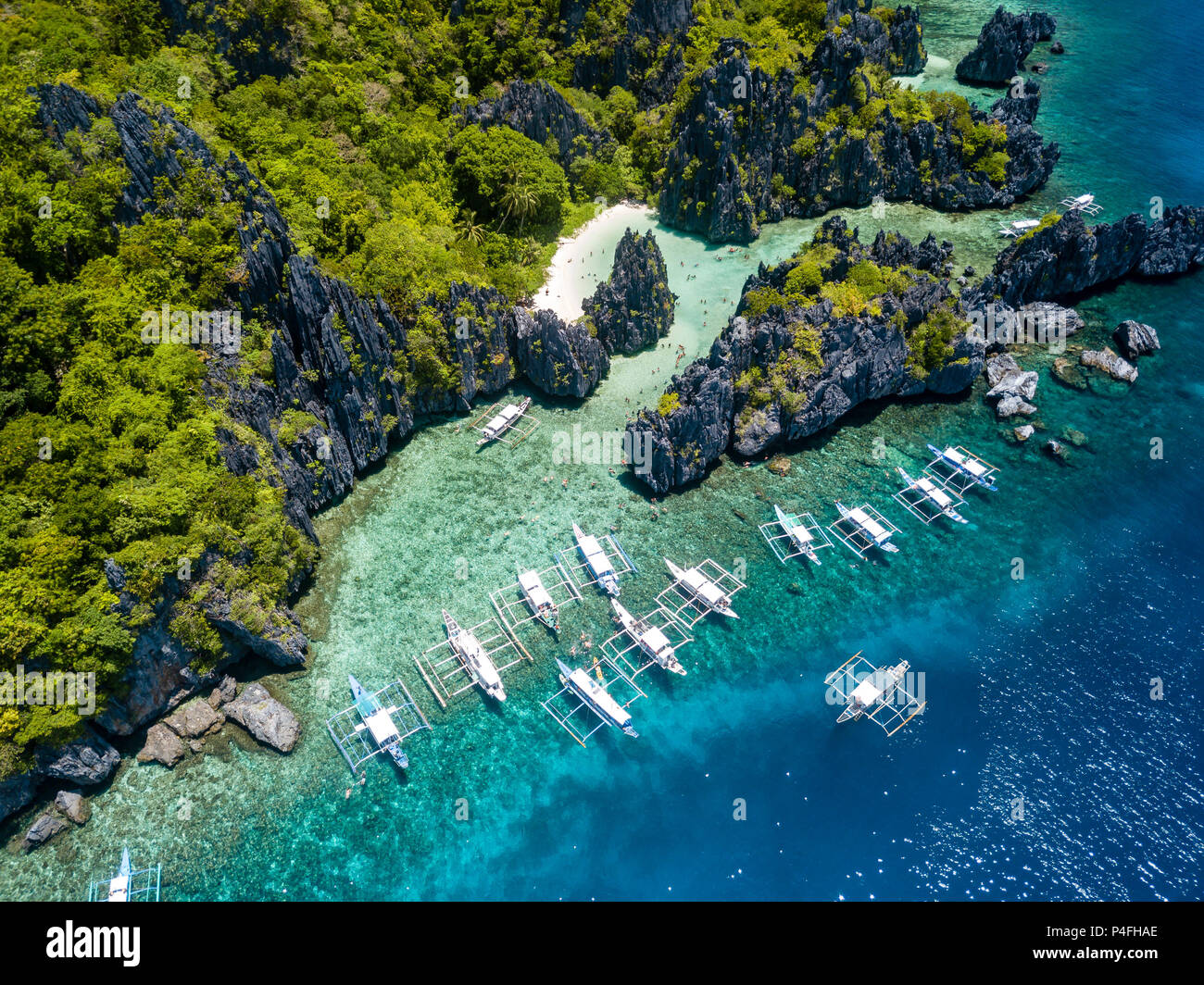 Aerial drone view of boats over a tropical coral reef and remote sandy beach (Hidden Beach, El Nido) Stock Photo