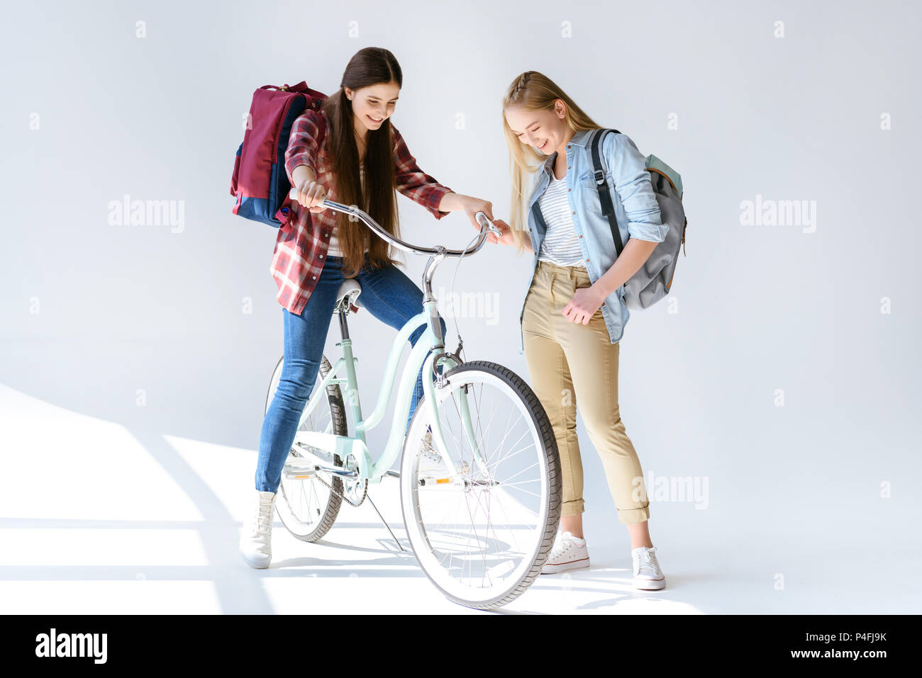 smiling caucasian teenage girls in casual clothing with bicycle isolated on white Stock Photo