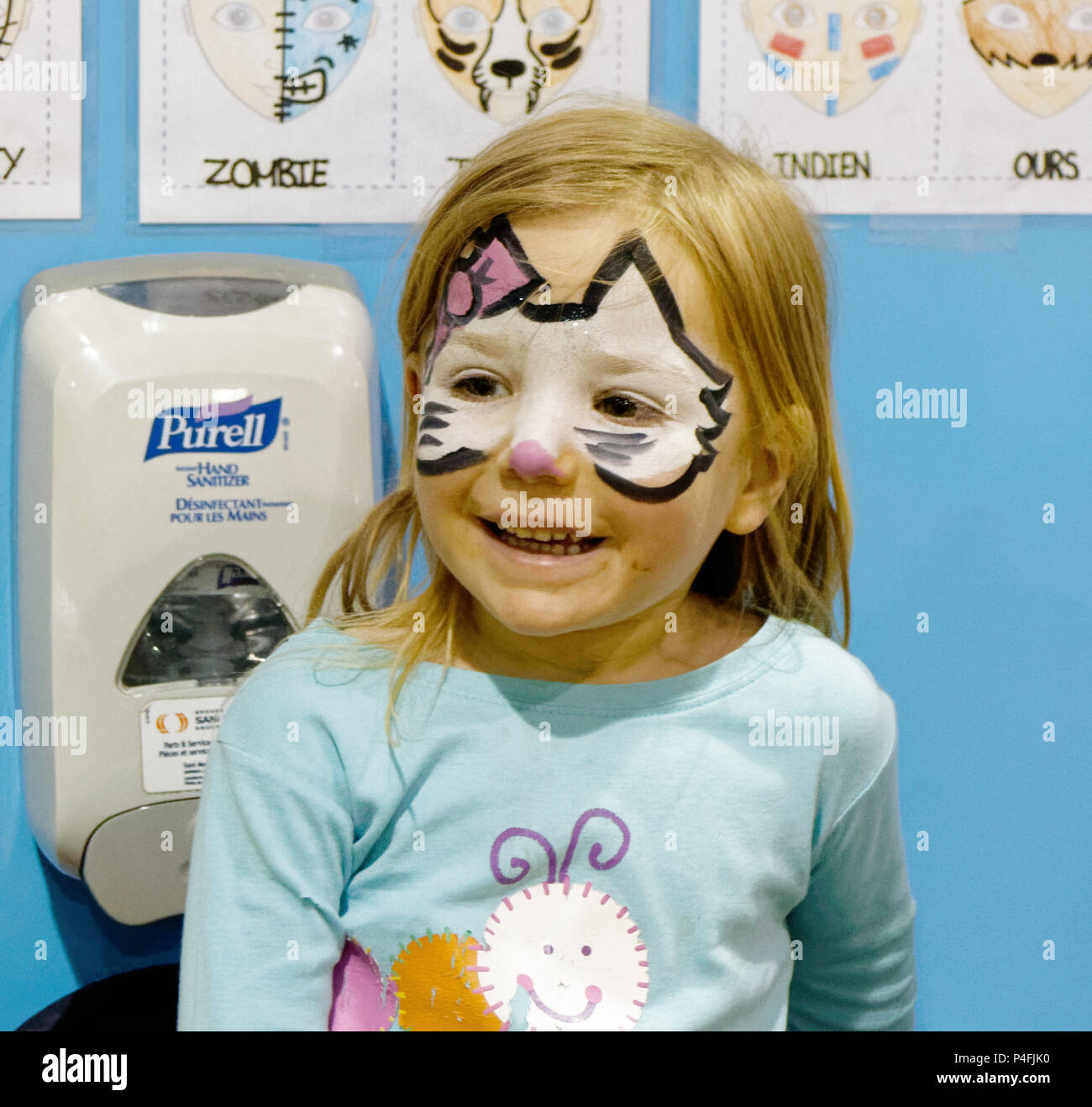 A three year old girl looking delighted with her new Hello Kitty face paint Stock Photo