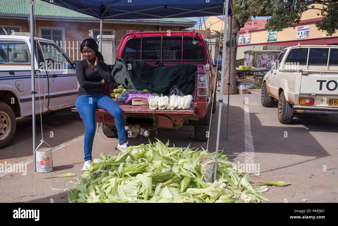 African lady street trader selling maize or corn cobs sitting on the