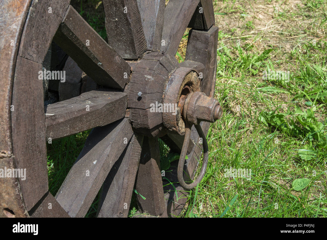 Fixing an old wooden wheel with a metal rim on a rural cart, close - up Stock Photo