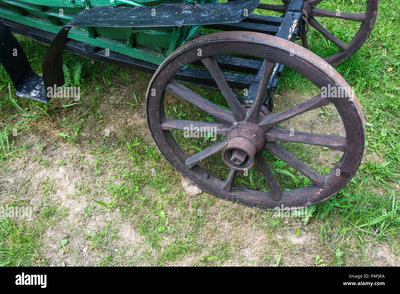 Old wooden wheel with a metal rim on a rural wagon, close-up Stock Photo