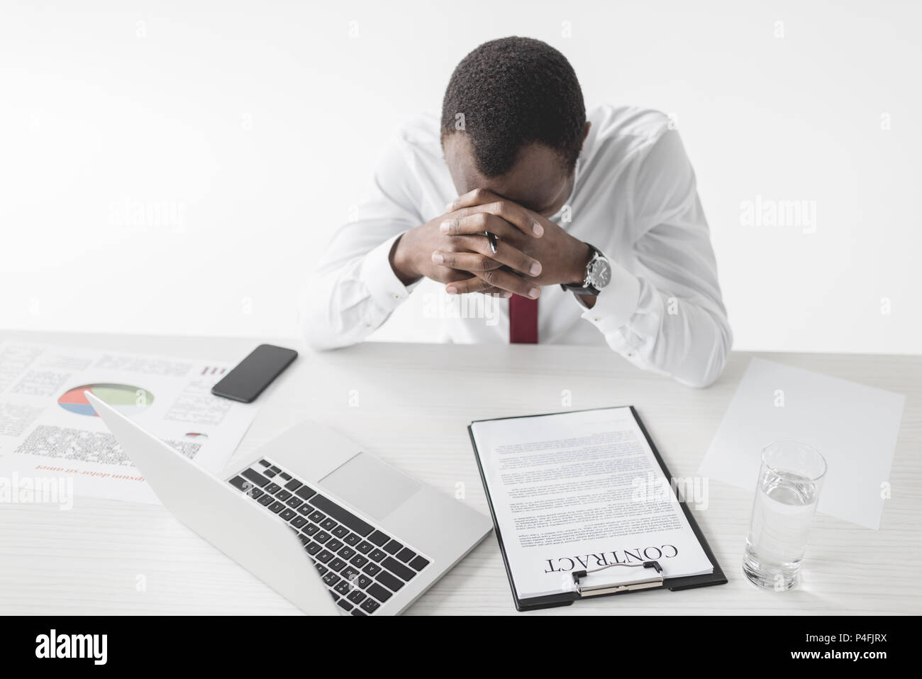 tired african american businessman sitting at workplace with laptop and documents isolated on grey Stock Photo