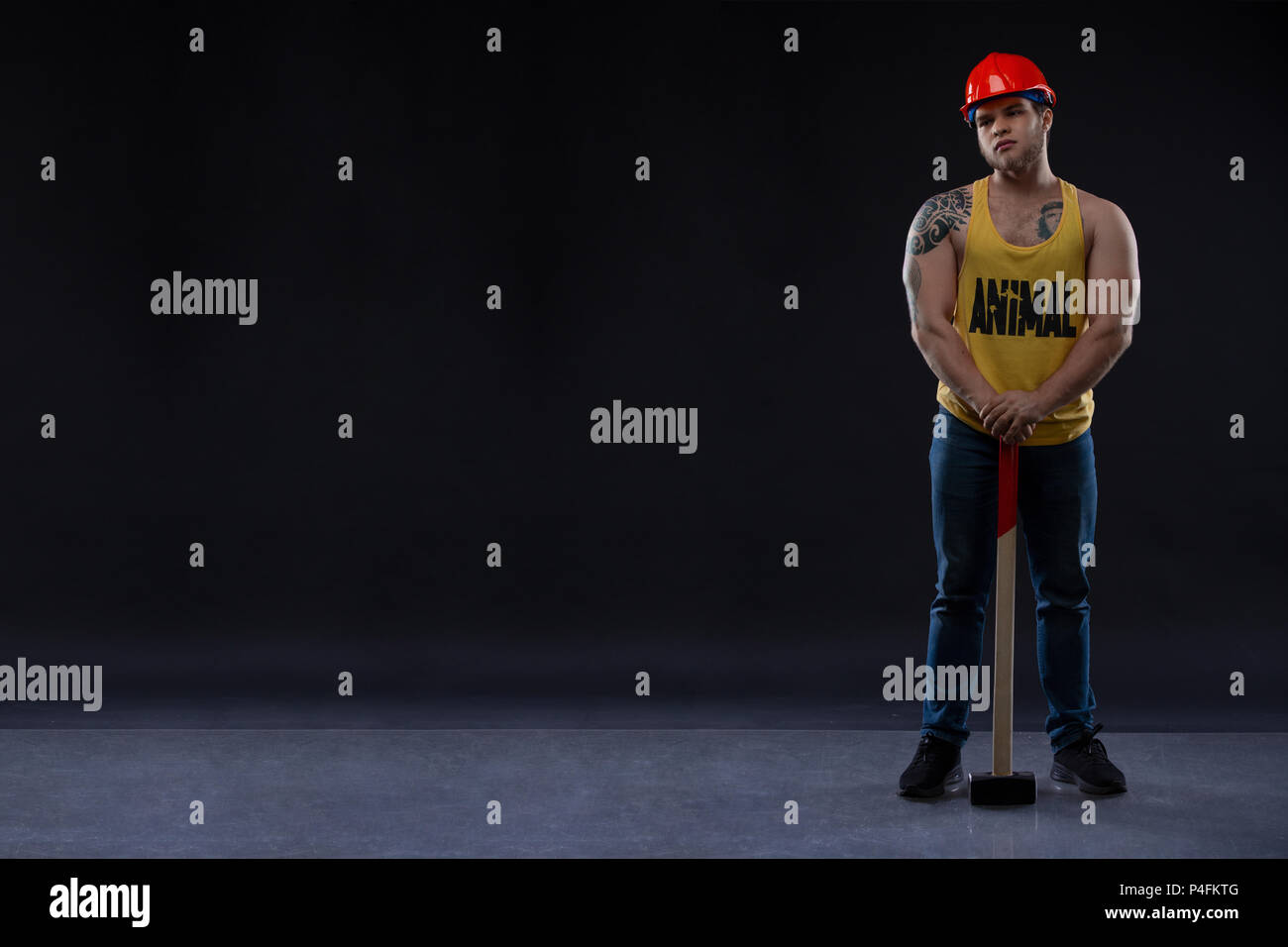 brutal Muscular worker man with a hammer. man in tattoos on a black background Stock Photo