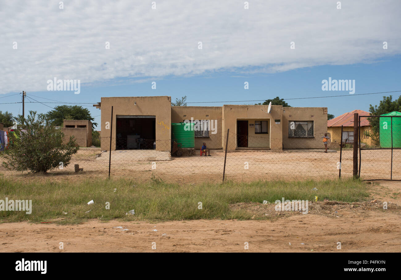 low income house in black African rural community in South Africa with  green water tank for water conservation and people outdoors Stock Photo
