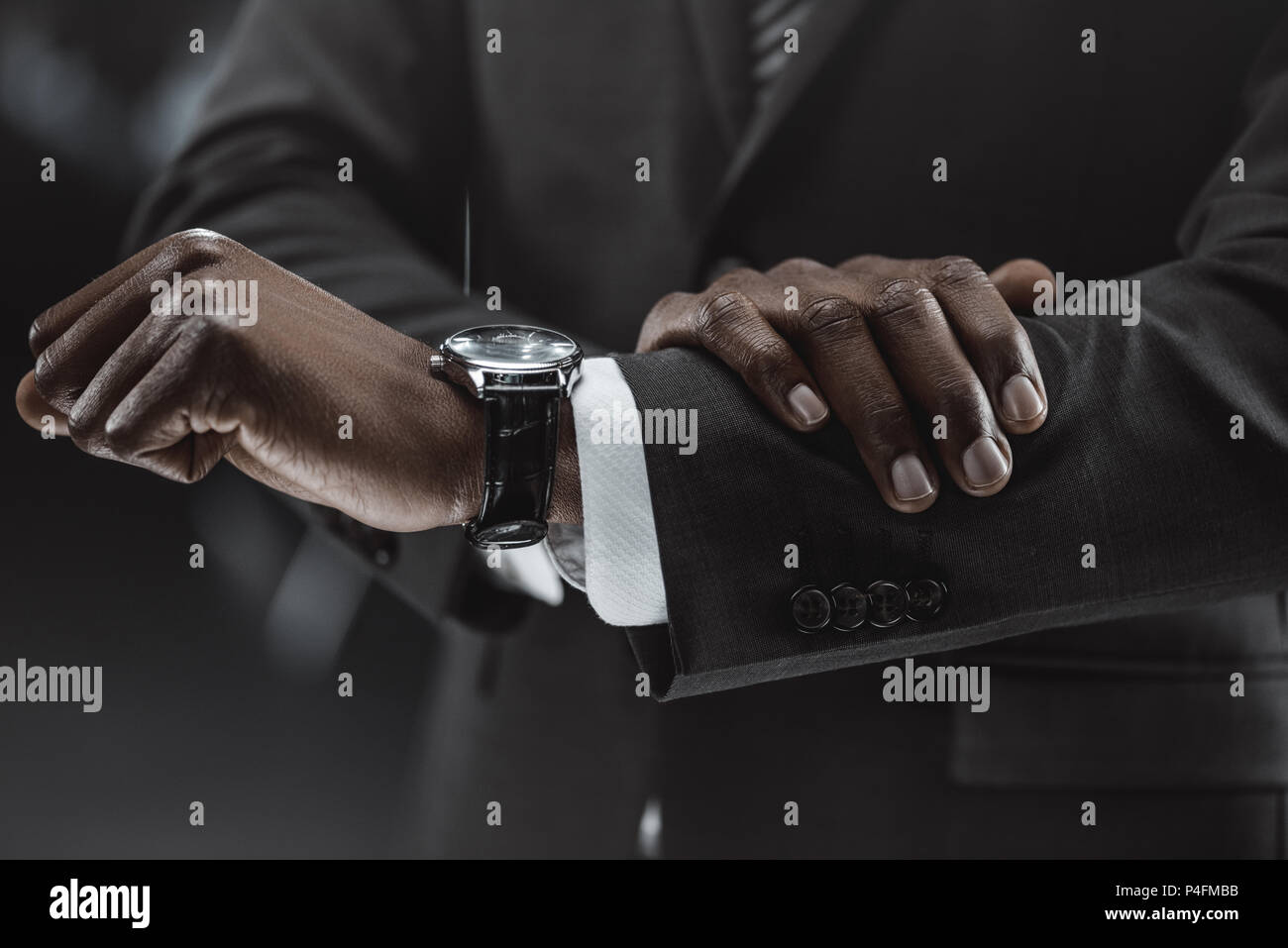 partial view of african american businessman checking time on watch ...