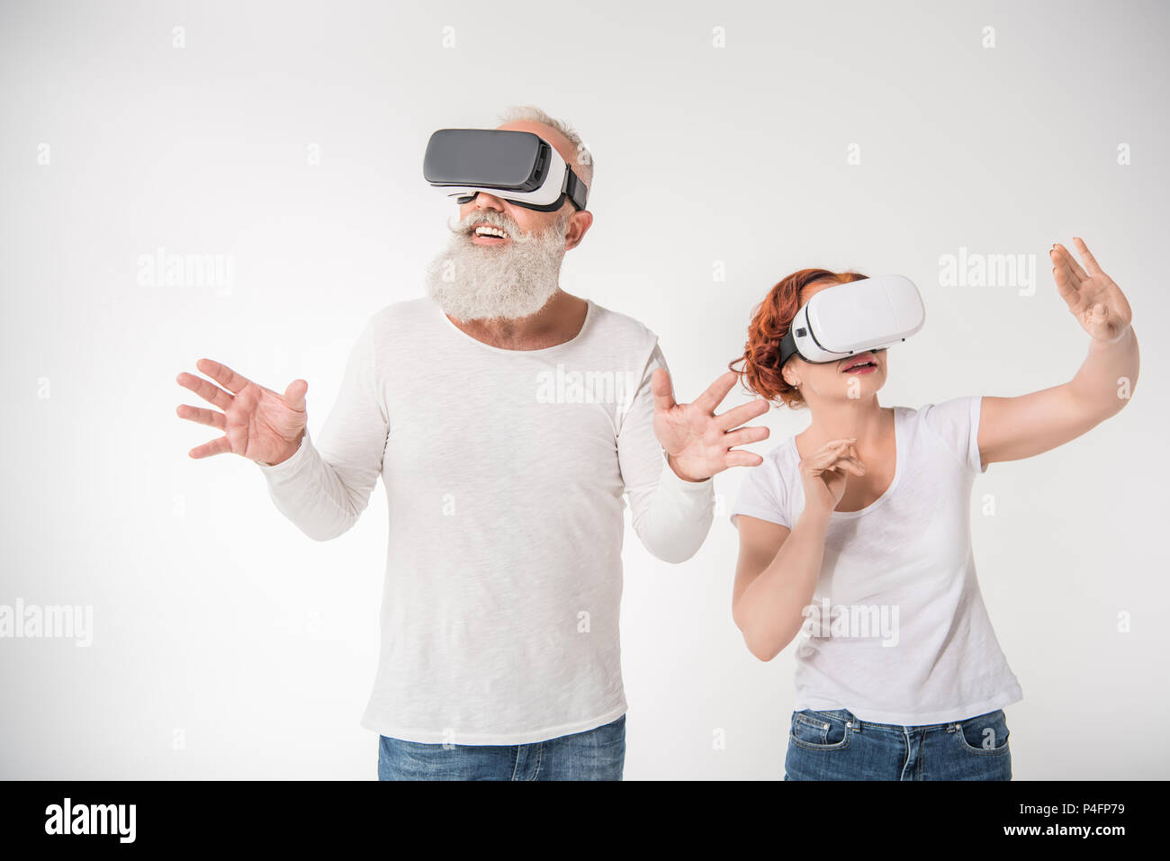 senior couple gesturing and using virtual reality headsets, isolated on white Stock Photo