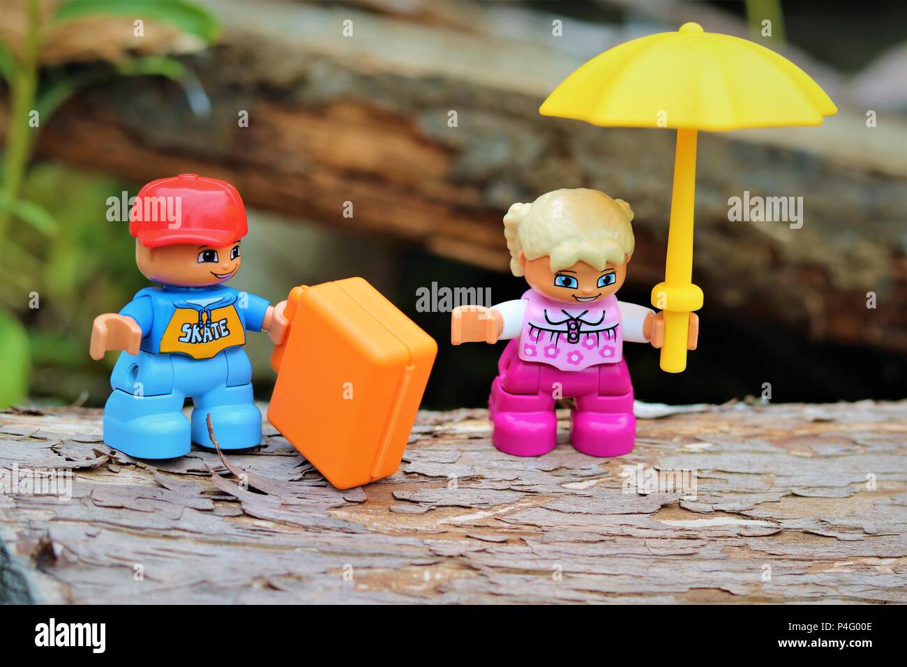 Duplo boy and girl characters with umbrella and briefcase against a blurred background - News Concept Stock Photo