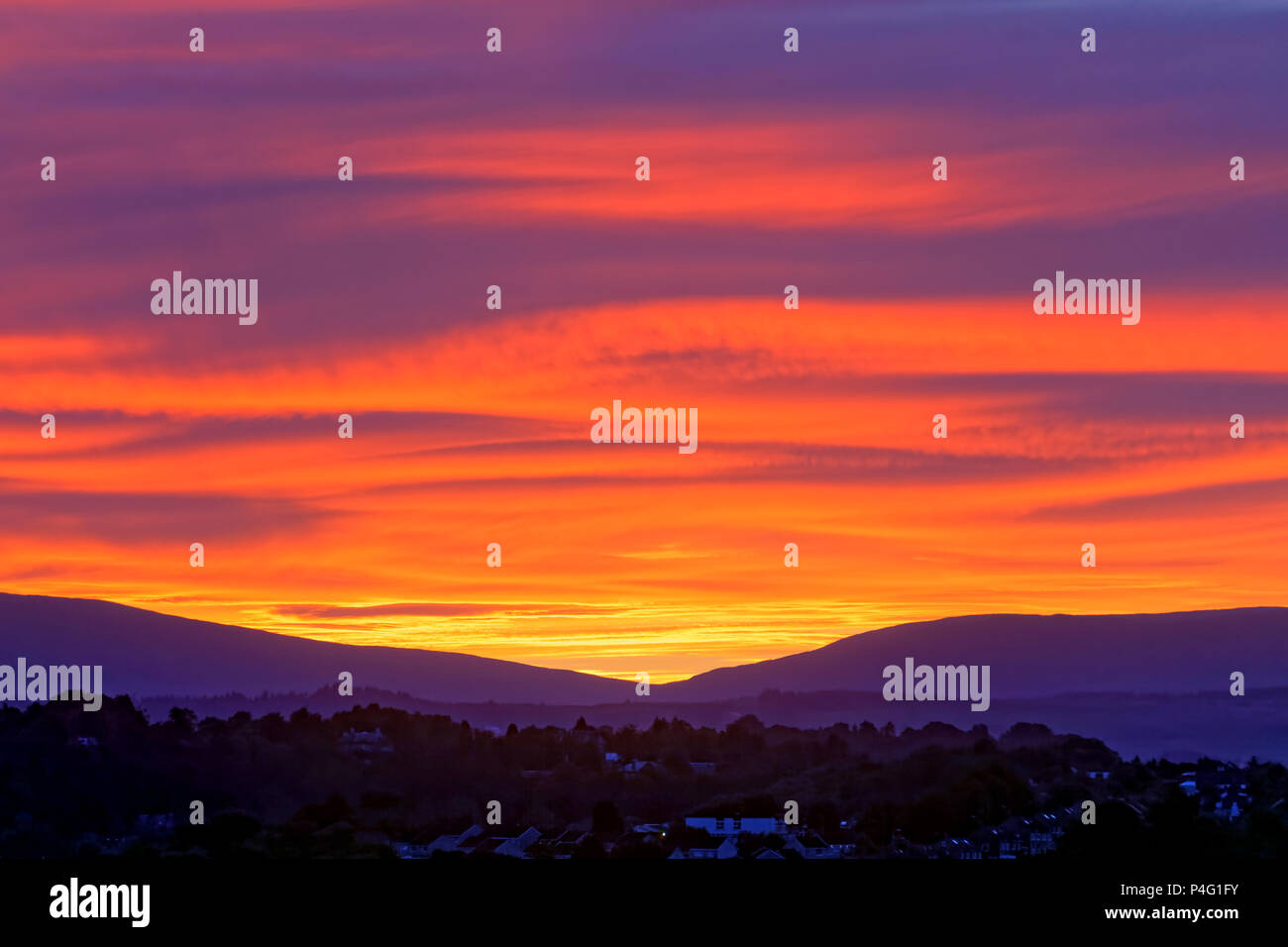 Glasgow, Scotland, UK 22nd June. UK Weather: Midsummer passes and a stunning  fiery sunrise for the beginning of summer as the gap in the Campsie fells  hills North of the city hosts a bright red start with wavy cloud formations taking on the rosy hue. Gerard Ferry/Alamy news Stock Photo