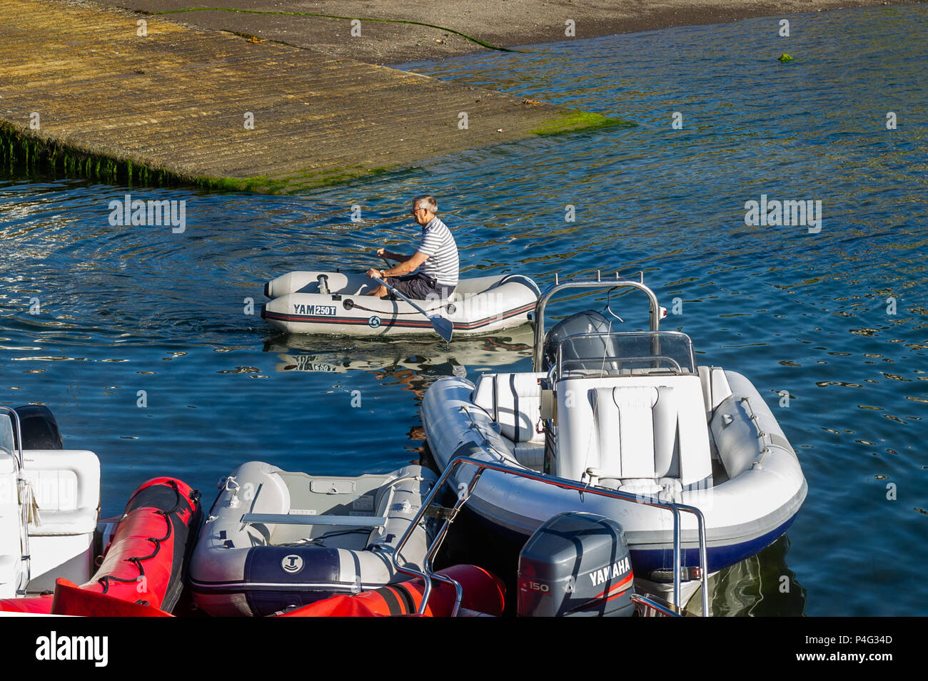 Schull, Ireland. 22nd June, 2018. A boater rows out to his boat in Schull Harbour to spend the day boating in and around Schull. Temperatures will rise over the coming days, reaching the mid-20's celsius by the middle of next week. Credit: Andy Gibson/Alamy Live News. Stock Photo