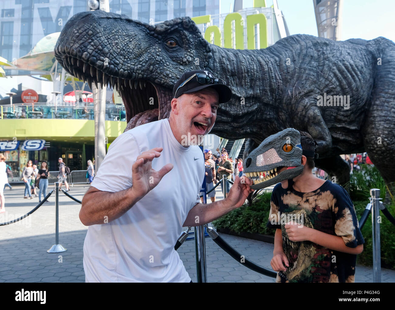 Los Angeles, USA. 21st June, 2018. People pose for pictures with a giant Tyrannosaurus rex statue at Universal CityWalk in Los Angeles, United States on June 21, 2018. For the promotion of the screening of the new film 'Jurassic World: Fallen Kingdom' on Universal Cinema Theatres, a colossal 3-ton Tyrannosaurus rex, a life-sized Gyrosphere original movie prop, as well as original costume, are displayed for public at Universal CityWalk. Credit: Zhao Hanrong/Xinhua/Alamy Live News Stock Photo