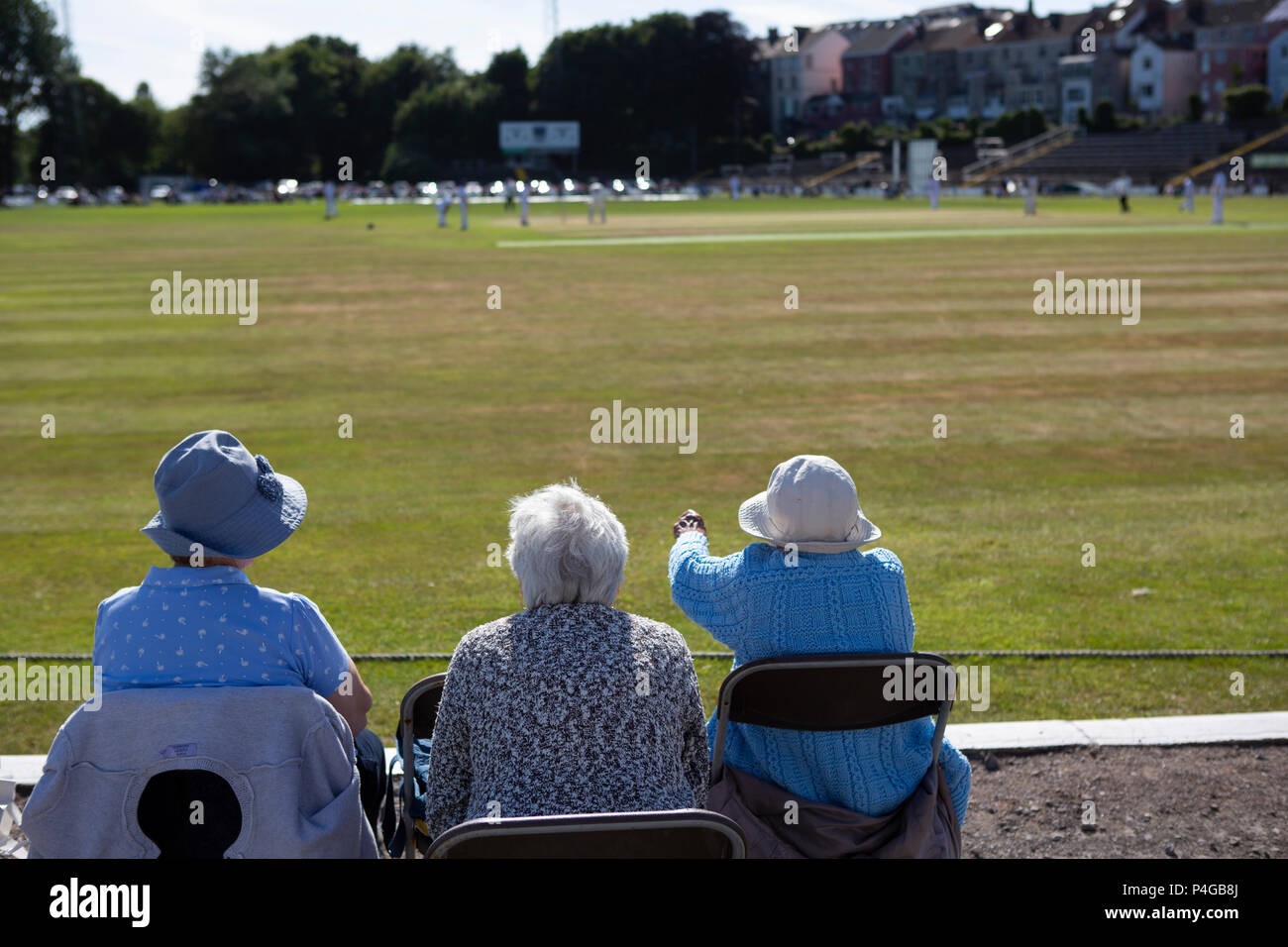 Three senior citizens enjoying watching cricket on a hot day in summer Stock Photo