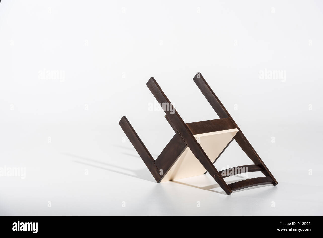 Classic dark wooden chair with white top lying on white floor in studio Stock Photo Alamy