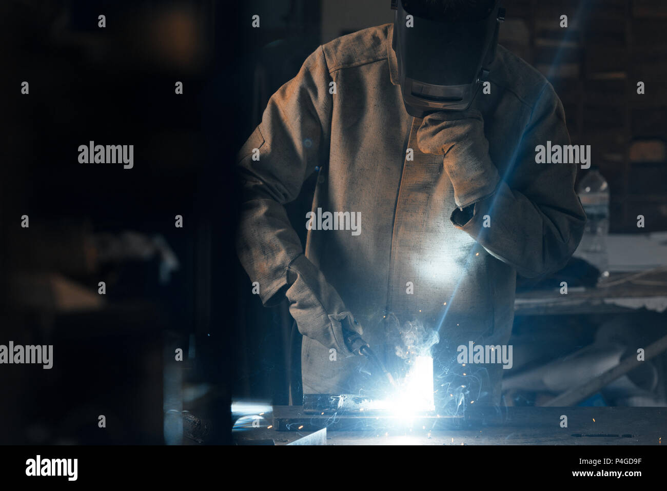 welder in protection mask working with metal at factory Stock Photo