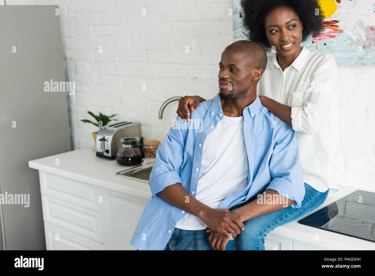 portrait of happy african american woman hugging husband in kitchen at ...
