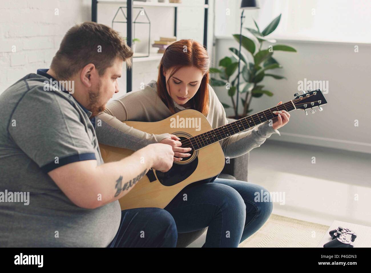 boyfriend teaching girlfriend playing acoustic guitar at home Stock Photo