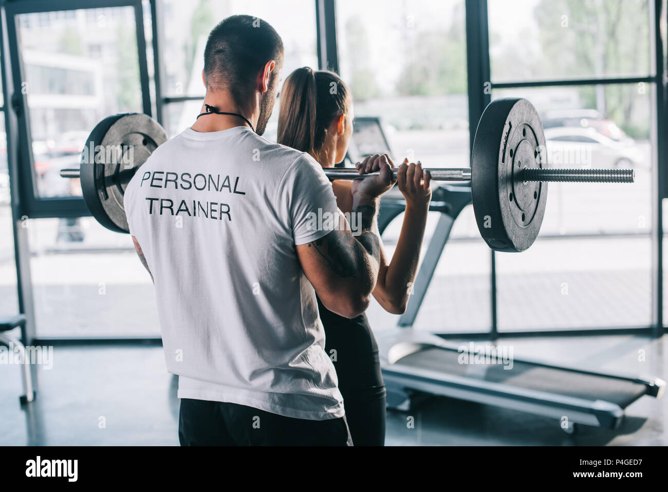 Male Personal Trainer Helping Sportswoman To Do Exercises With Barbell At Gym Stock Photo Alamy