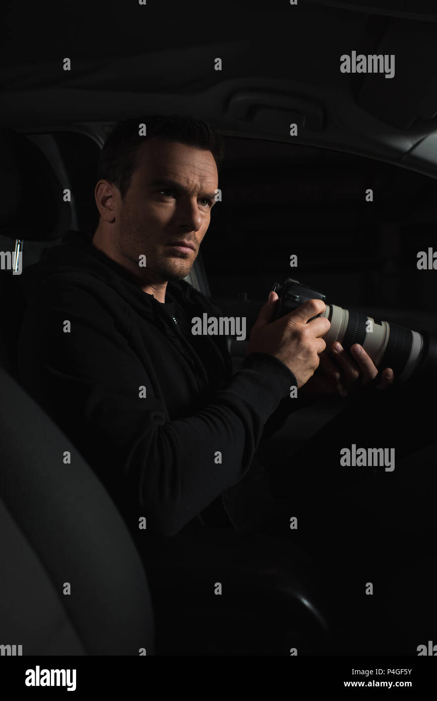 serious male undercover agent doing surveillance by binoculars and holding paper  cup of coffee Stock Photo - Alamy