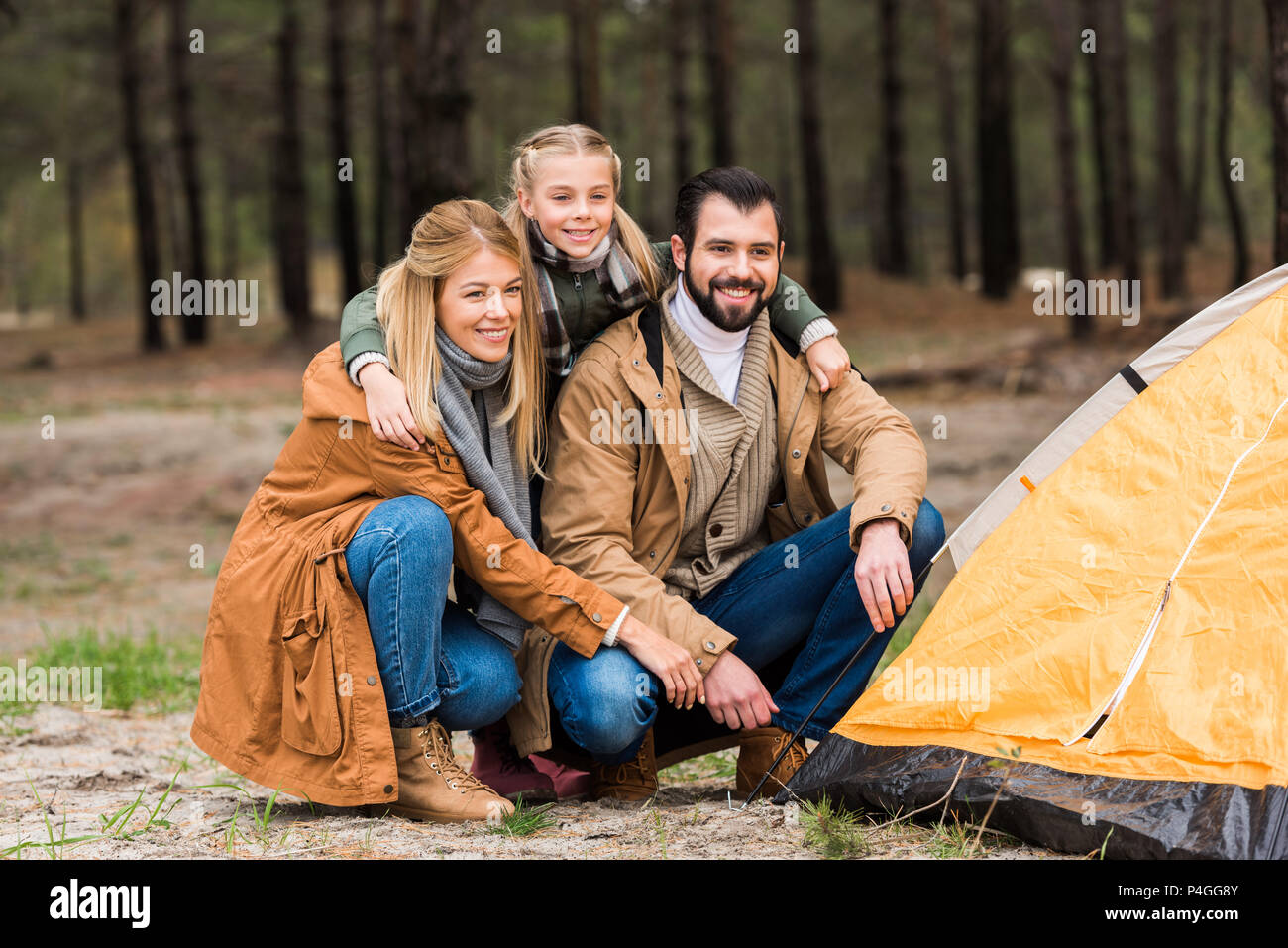 young family installing tent together in pine forest Stock Photo