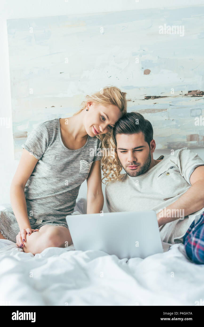 smiling young couple using laptop together in bed Stock Photo - Alamy